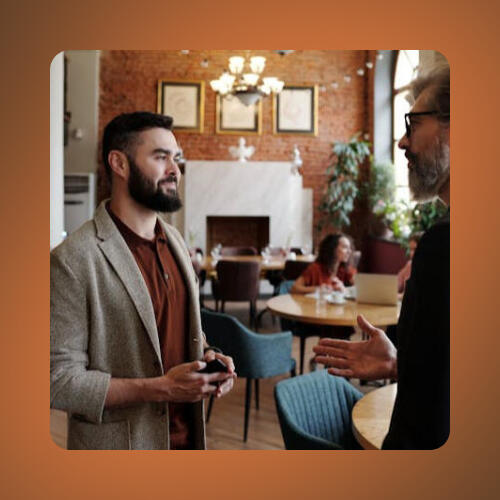 Échangez avec des influenceurs pertinents" Un propriétaire d'un restaurant à Mulhouse discute avec un influenceur dans un café pour organiser une collaboration en Alsace.